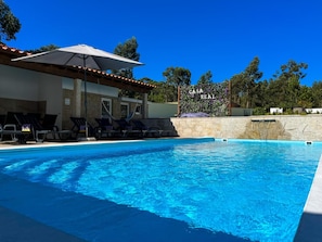 A swimming pool with lounge chairs and a pergola with an umbrella.