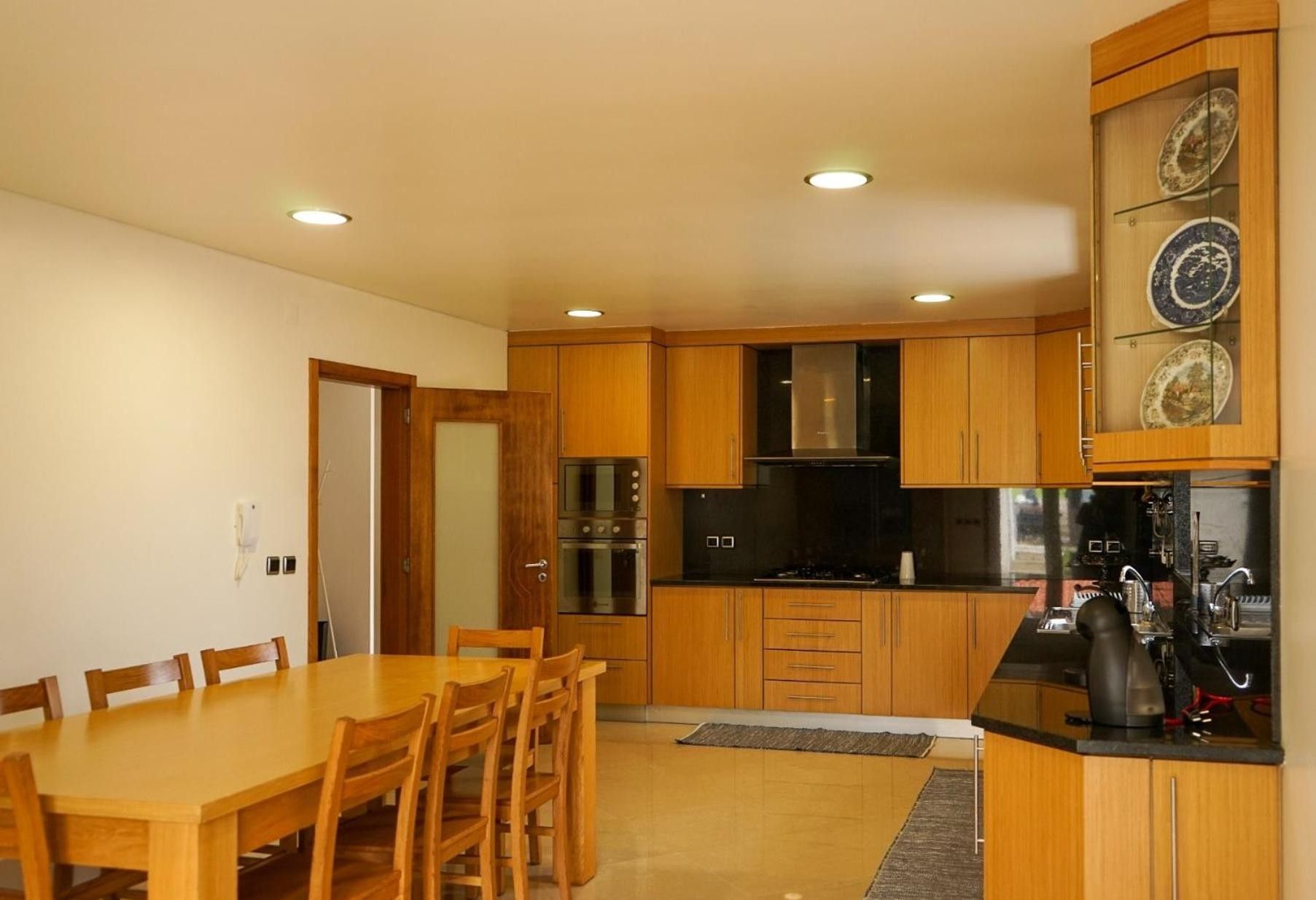 Une cuisine compacte avec des meubles en bois, une table à manger avec des chaises et une cuisinière encastrée.