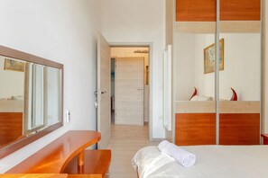 Ein Hotelzimmer mit einem hölzernen Bett, einem Nachttisch, einem Spiegel und einer Tür zu einem Badezimmer.