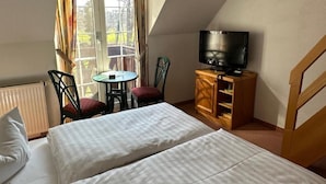 A bedroom with two beds, a television, a small table, and a chair. - Hotel Am Spreebogen (Burg (Spreewald))