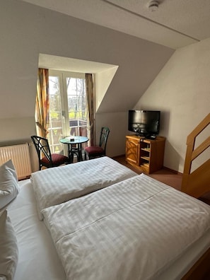A bedroom with two beds, a television, a small table, and a chair. - Hotel Am Spreebogen (Burg (Spreewald))