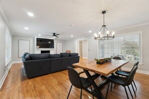 A modern living room with a dark sofa, a wooden dining table, and black chairs. - Poolside Family Fun, Great Home Great Area (Oklahoma City)