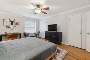 A bedroom with a bed, a ceiling fan, a TV, a wardrobe, a desk with a chair, and a window with blinds. - Poolside Family Fun, Great Home Great Area (Oklahoma City)