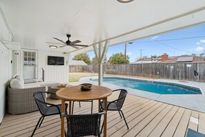 An outdoor patio with a pool, a ceiling fan, and a seating area with a table and chairs. - Poolside Family Fun, Great Home Great Area (Oklahoma City)