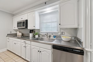 A kitchen with white cabinetry, stainless steel appliances, a dishwasher, and a window with blinds. - Poolside Family Fun, Great Home Great Area (Oklahoma City)