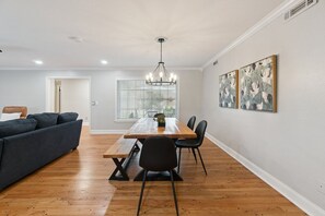 Een eetgedeelte met een houten tafel, zwarte stoelen en een kroonluchter.