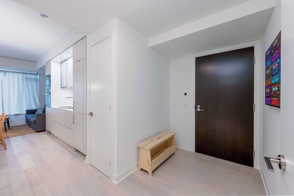 Ein modernes Interieur mit einer dunklen Tür, einer Sitzbank und einem Zimmer mit Bett und Fenster.