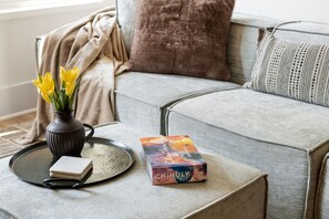 Un salon avec un canapé gris, un vase rempli de fleurs jaunes, un plateau sur lequel repose un livre intitulé « CHIHULY 365 DAYS », et une petite table.