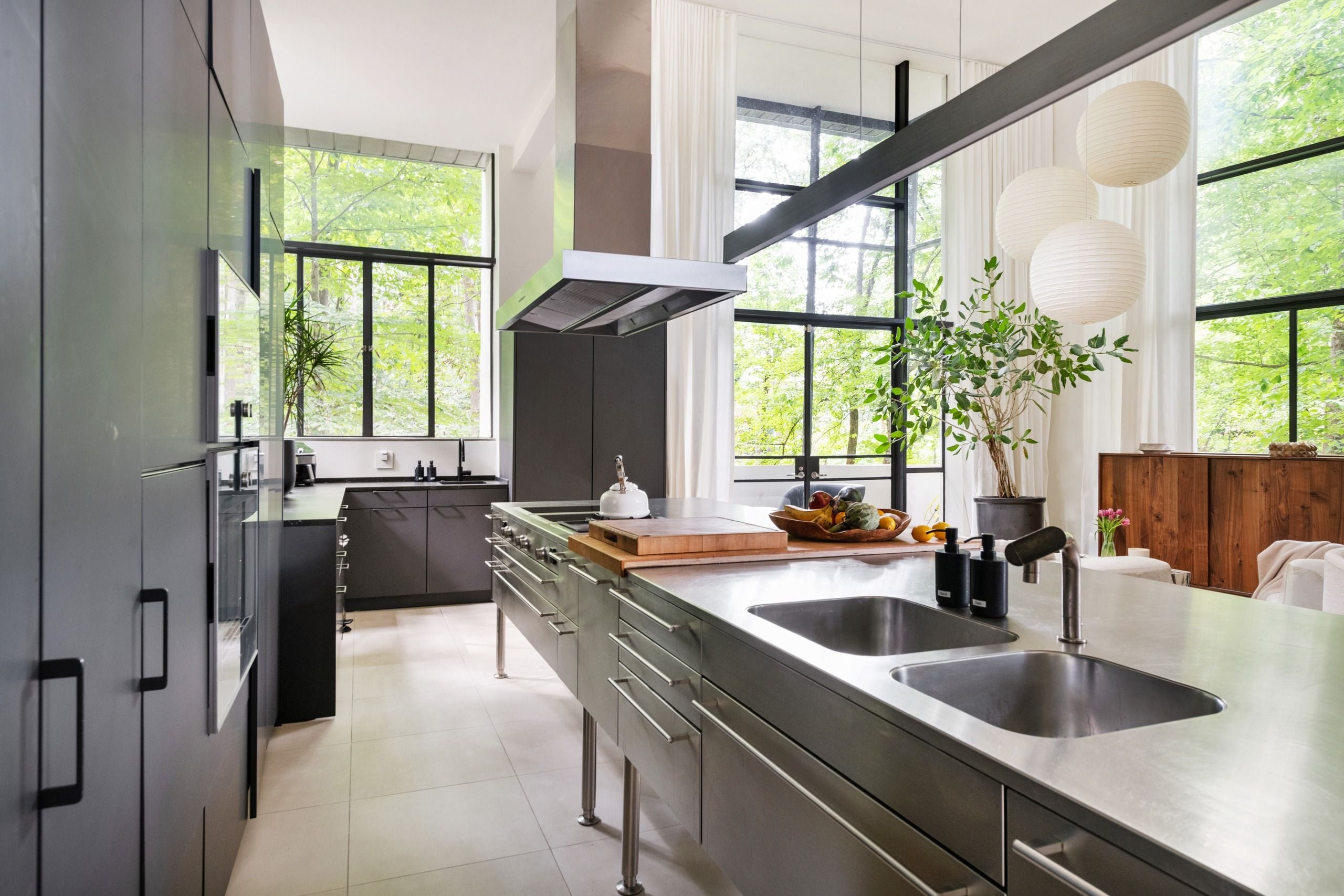 Una cocina moderna con electrodomésticos de acero inoxidable, una isla grande con pileta y amplias ventanas con vista a zonas verdes.