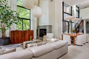 A spacious living room with a large sofa, a wooden cabinet, a fireplace, and a staircase leading to an upper level. - Crystal Claire (Atlanta)