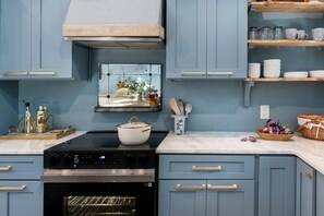 A kitchen with a stove, oven, and various kitchen items on the counter. - Atelier Bleu (Atlanta)