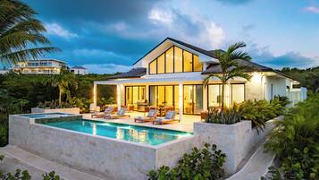 A modern house with a swimming pool, outdoor seating, and lush greenery.