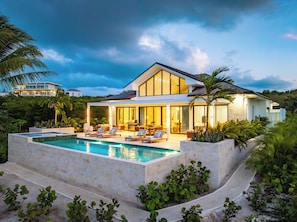 A modern house with a swimming pool, outdoor seating, and lush greenery.