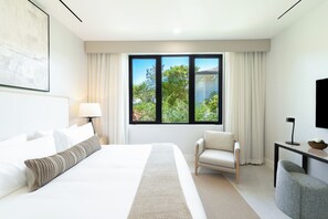 A modern hotel room with a large bed, a seating area, and a window with a view of greenery.