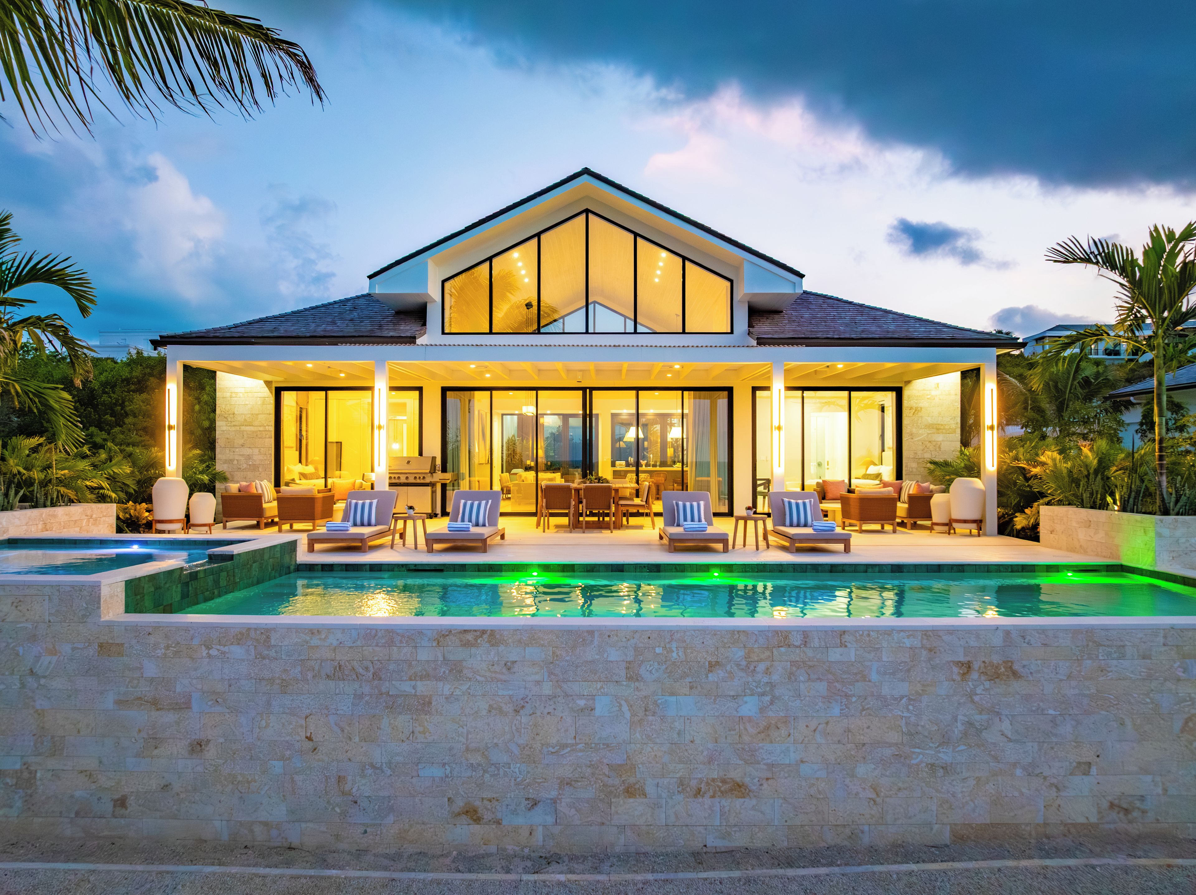 A modern house with a swimming pool, large windows, and outdoor seating.