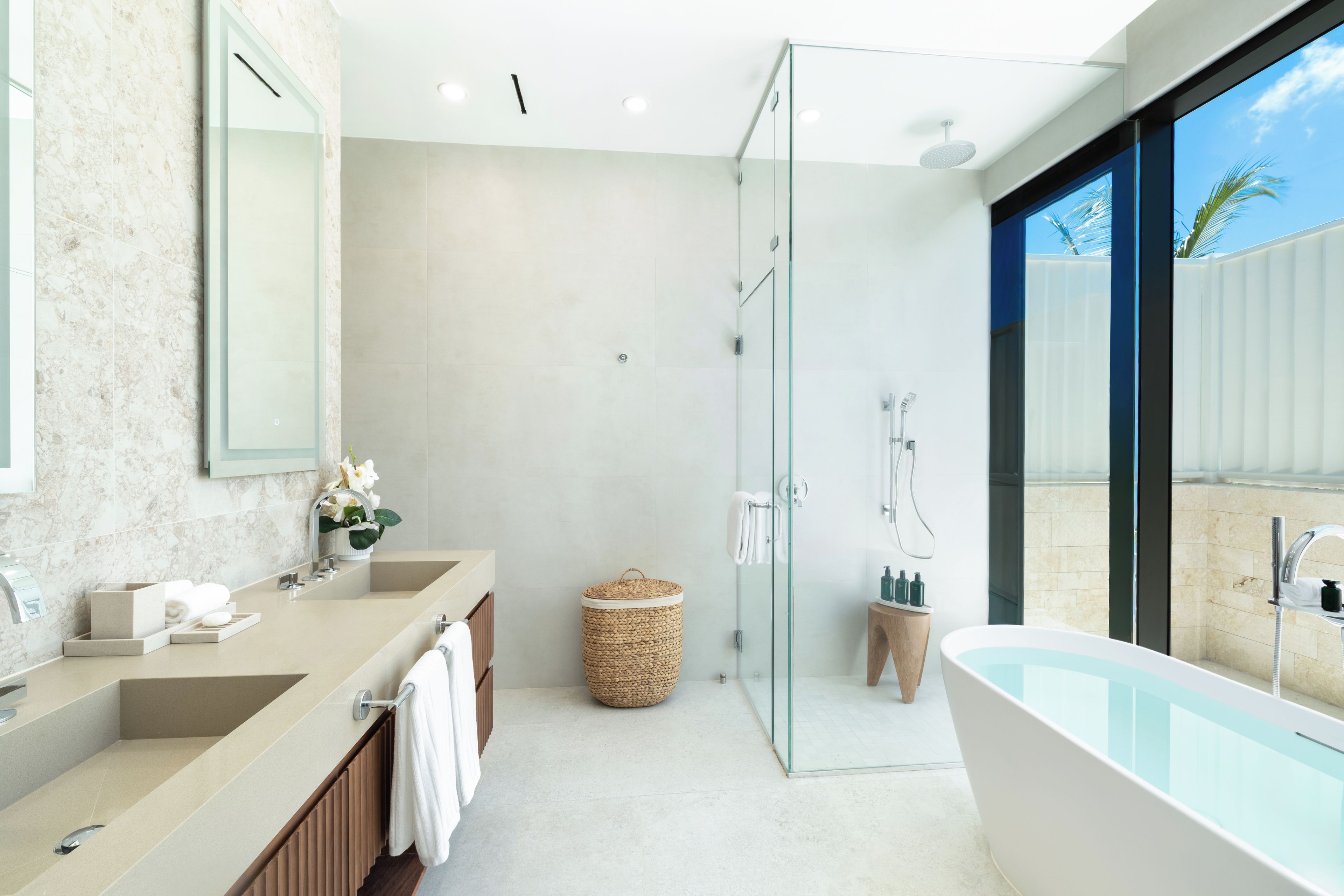 A modern bathroom with a glass-enclosed shower, a freestanding bathtub, and a vanity with dual sinks.