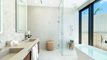 A modern bathroom with a glass-enclosed shower, a freestanding bathtub, and a vanity with dual sinks.