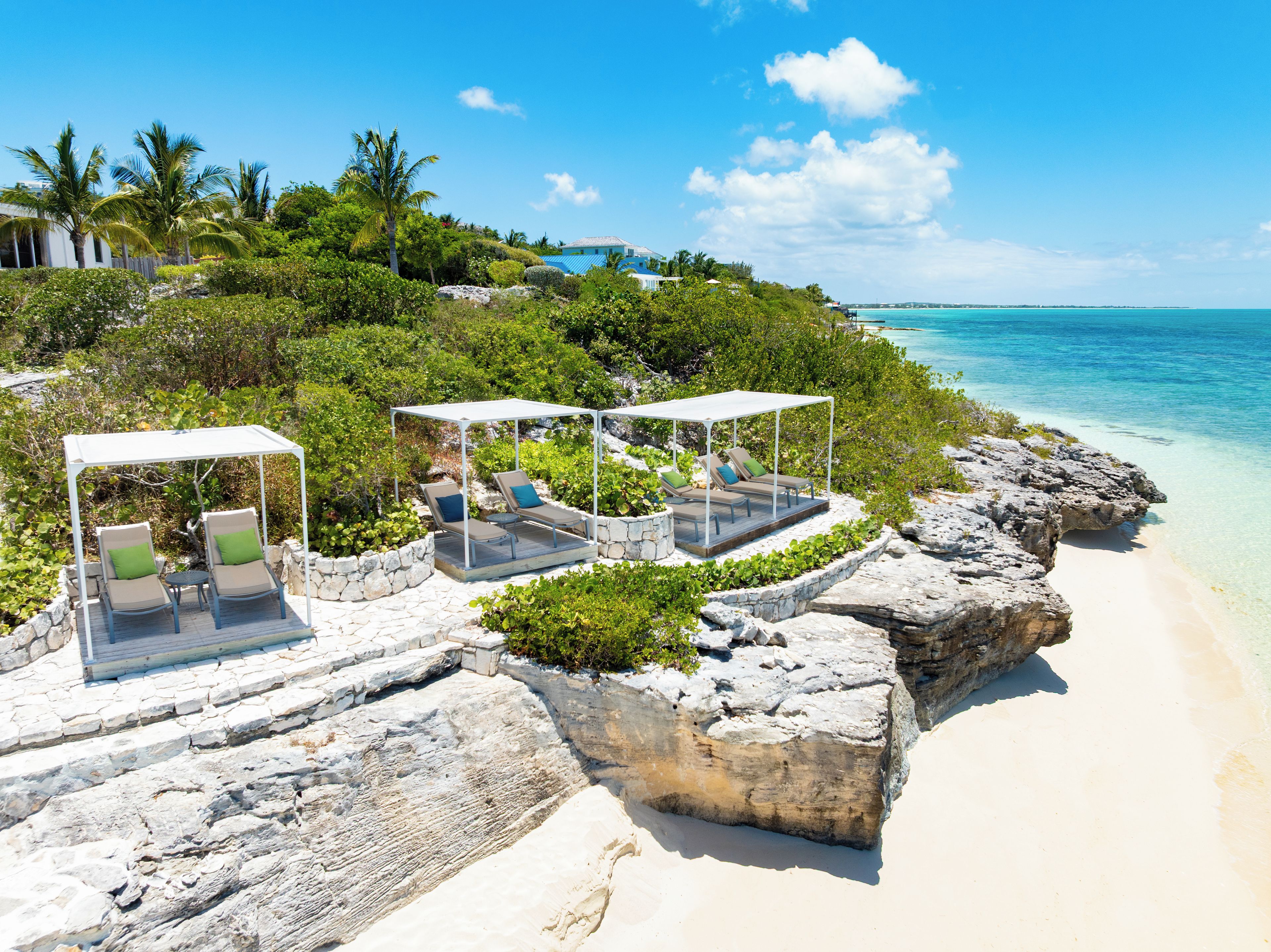 Un resort frente al mar con zonas de estar al aire libre, vista al océano y un litoral rocoso.