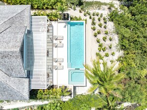 Vista aérea de un resort con piscina, tumbonas y zona de playa.