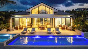 Una casa moderna con piscina, ventanas amplias y mobiliario de exterior.