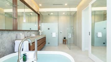 Een moderne badkamer met een vrijstaand bad, een douche met glazen wanden en een wastafel met een marmeren aanrecht.
