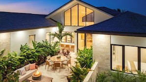 Una casa moderna con patio, mobiliario exterior y un pozo de fuego.