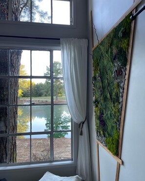 A room with a large window, a painting on the wall, and a curtain. - Tiny treehouse- outdoor shower- pond fishing! (Boaz)