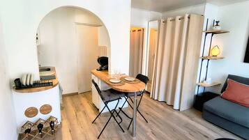 Ein gemütlicher Wohnbereich mit Essplatz, einer Couch und einem kleinen Tisch mit Lampe.