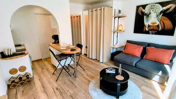 Ein stilvoller Wohnraum mit Essbereich, einer Couch, einem Couchtisch und einem Gemälde von einer Kuh.