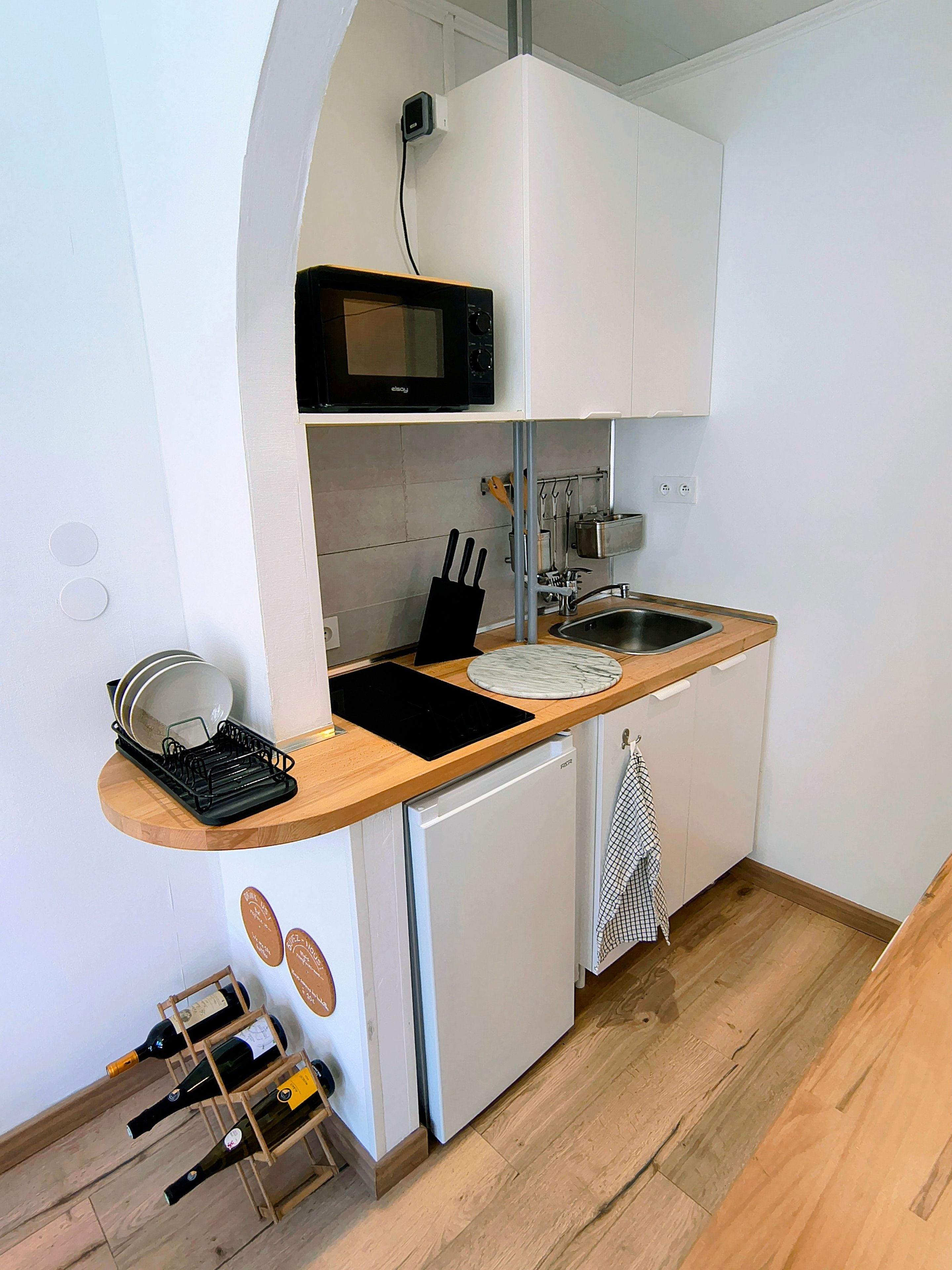 Una cocina compacta con microondas, pileta y heladera pequeña.