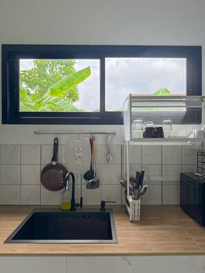 A kitchen with a window, a sink, a cutting board, and utensils. - 3BR near Old Town & Chillva Market - 8 Guests (Mueang Phuket)