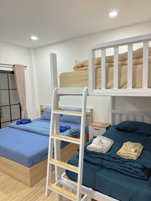 Une chambre de dortoir avec des lits superposés, une échelle, une table de chevet et une armoire.