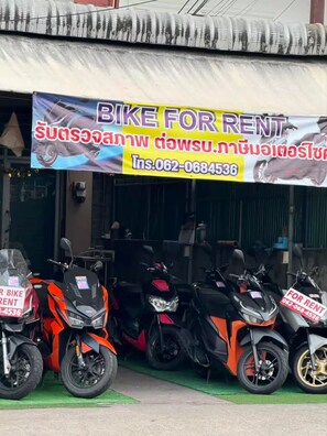 Un magasin de location de motos avec plusieurs motos garées devant.