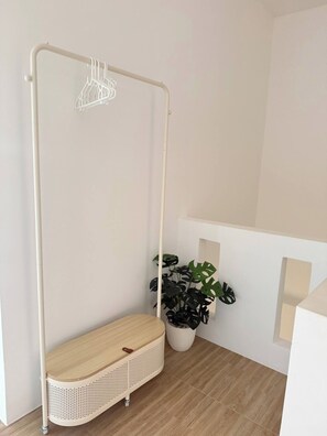 Une pièce avec un fauteuil suspendu, une plante en pot et un mur blanc.