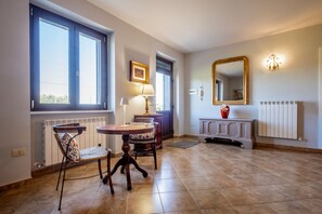 Ein Zimmer mit Esstisch, Stühlen, Heizkörper, Spiegel und Fenster.