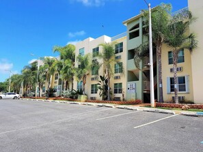 A multi-story building with a parking lot in front. - Gated Complex, Pool, Balcony, Near Attractions (Boquerón)