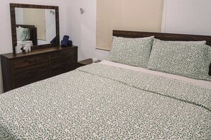 Ein Schlafzimmer mit Bett, Kommode und Spiegel.