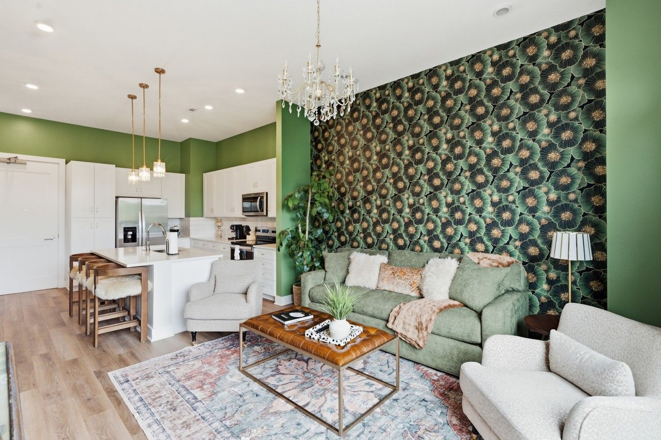 A modern living room with a green accent wall, a sofa, a coffee table, and a chandelier.