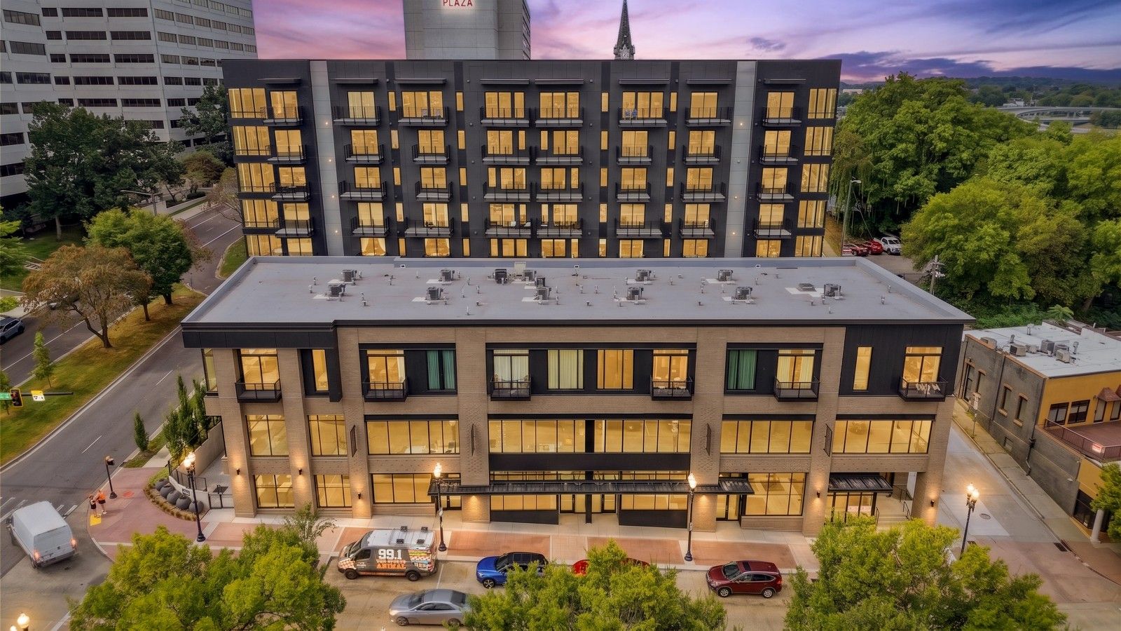 Ein mehrstöckiges Gebäude mit modernem architektonischen Design, mit einer flachen Dachkonstruktion, großen Fenstern und einem Parkplatz davor.