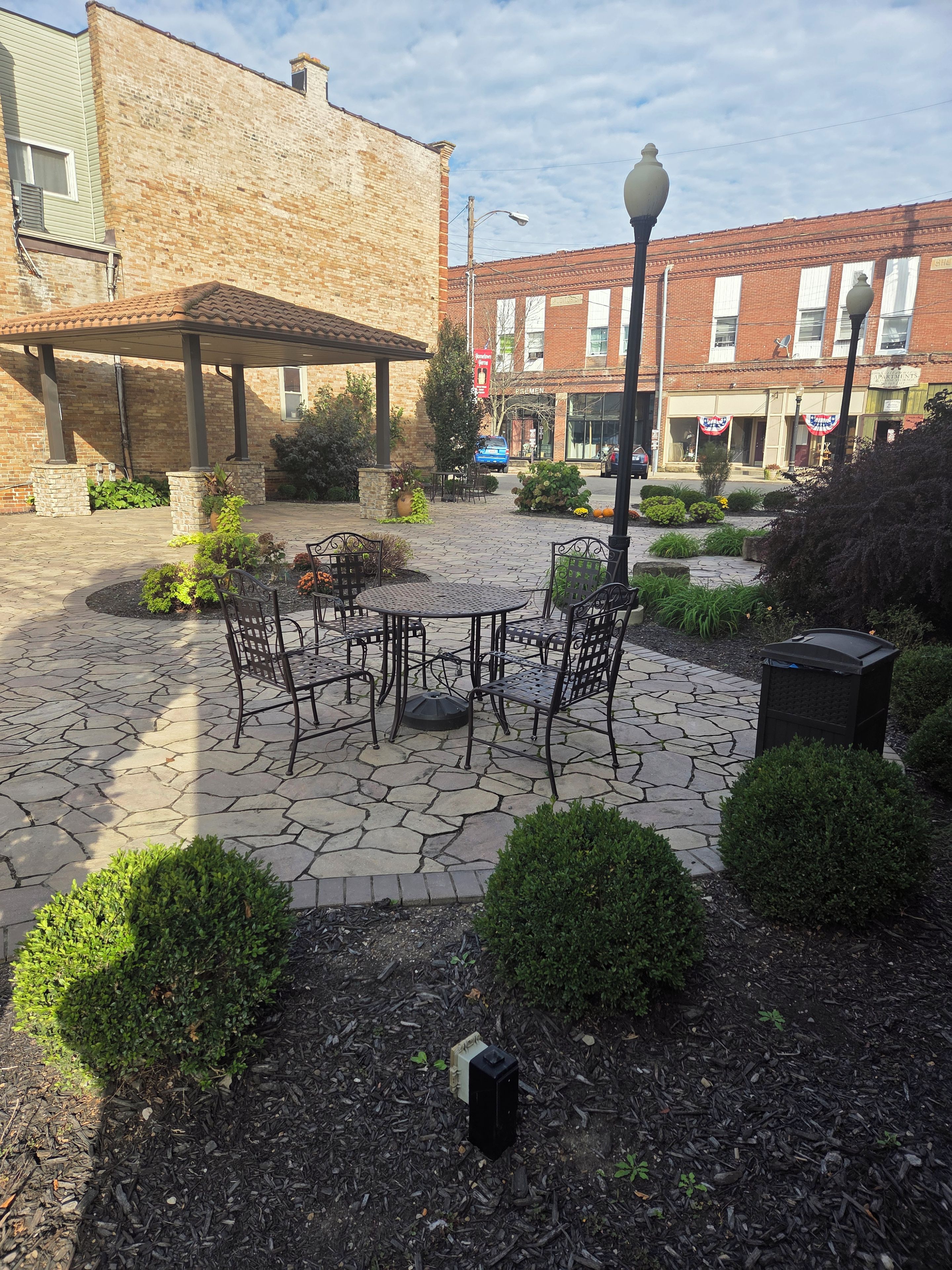 A courtyard with stone flooring, outdoor seating, and surrounding greenery.
