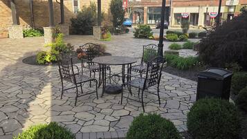 A courtyard with stone flooring, outdoor seating, and surrounding greenery.