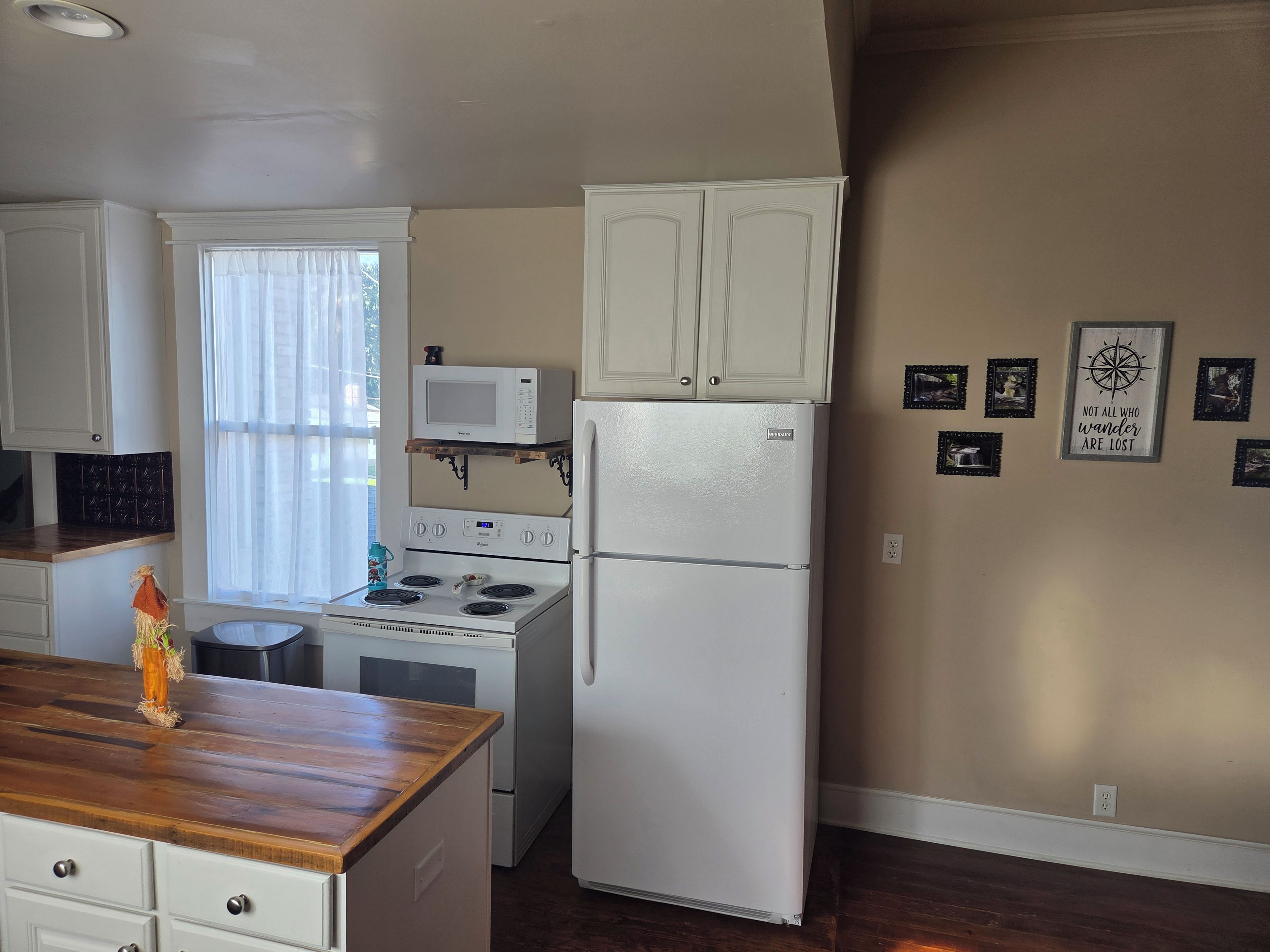 A kitchen with white cabinets, a microwave, a stove, and a refrigerator.