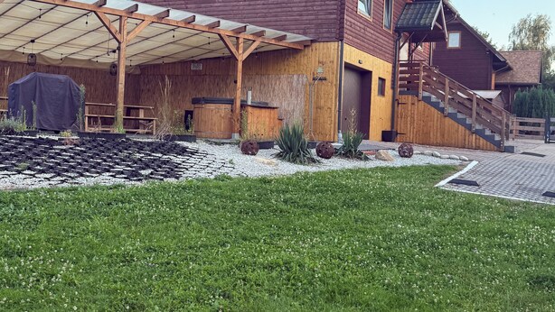 Et træhus med en overdækket terrasse og en lille have.