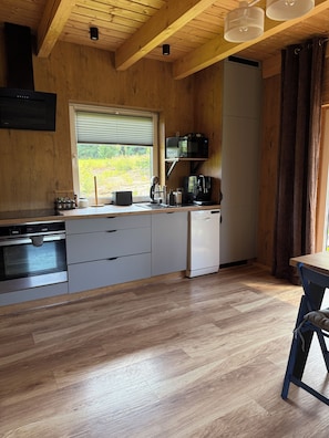 A modern kitchen with wooden cabinetry, a built-in oven, a microwave, and a coffee machine.