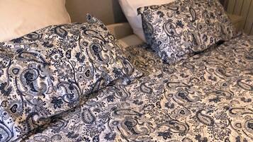 Un lit avec une couvre-lit à motifs et deux oreillers.