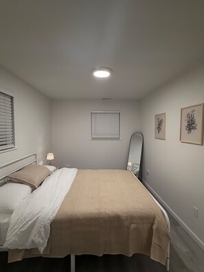 A bedroom with a bed, a bedside lamp, a window with blinds, a ceiling light, and two framed pictures on the wall. - Cozy 2 Bedroom Near Uptown, Dining & Fun (Charlotte)