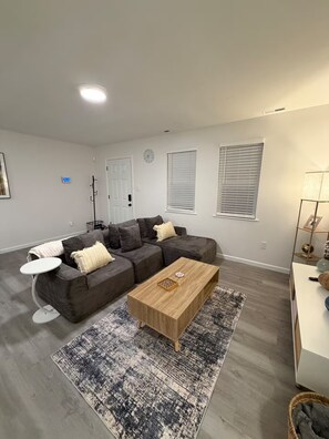 A modern living room with a grey sectional sofa, a wooden coffee table, and a patterned rug. - Cozy 2 Bedroom Near Uptown, Dining & Fun (Charlotte)