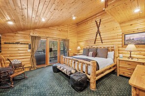 Een slaapkamer in een blokhut met een houten bed, een bankje, een stoel en een kleine tafel.