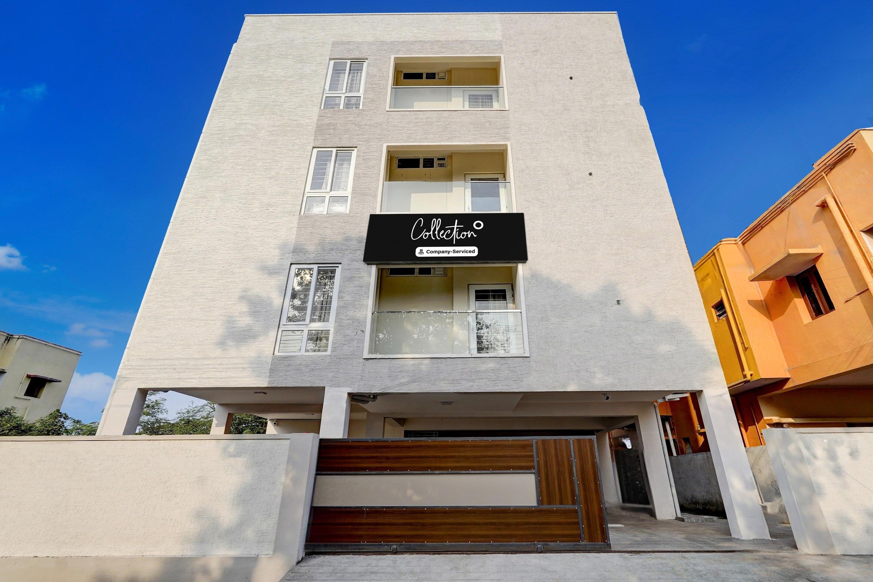 A multi-story building with a flat facade, a company-serviced sign, and a visible entrance with a wooden door.