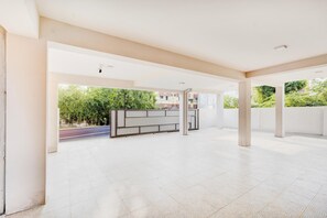 A spacious indoor area with a tiled floor, a bench, and a view of greenery outside. - Super Collection O Sholinganallur (Chennai)